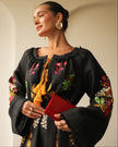 Close-up of black embroidered linen kaftan showing floral bodice, mustard tassel ties, and bell sleeves — Zalxndra Resort