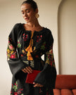 Editorial portrait of model in black floral embroidered linen kaftan maxi dress with mustard tassel ties and red clutch — Zalxndra Resort