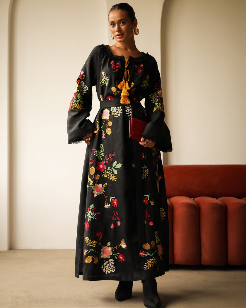 Full-length view of black floral embroidered linen kaftan maxi dress styled with black ankle boots and red clutch — Zalxndra Resort