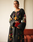 Model wearing black floral embroidered linen kaftan maxi dress styled with a red clutch and gold hoop earrings — Zalxndra Resort