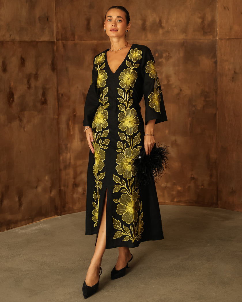 Black linen kaftan maxi dress with bold gold floral embroidery, V-neck, and front slit styled with feather clutch - Zalxndra Resort