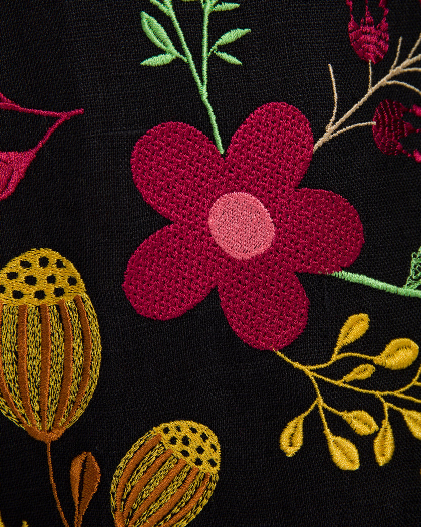 Macro close-up of multi-color floral embroidery detail and linen weave texture on Zalxndra Resort kaftan dress