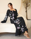 Black linen kaftan maxi dress with pastel floral embroidery and lilac tassel ties styled in lifestyle setting - Zalxndra Resort