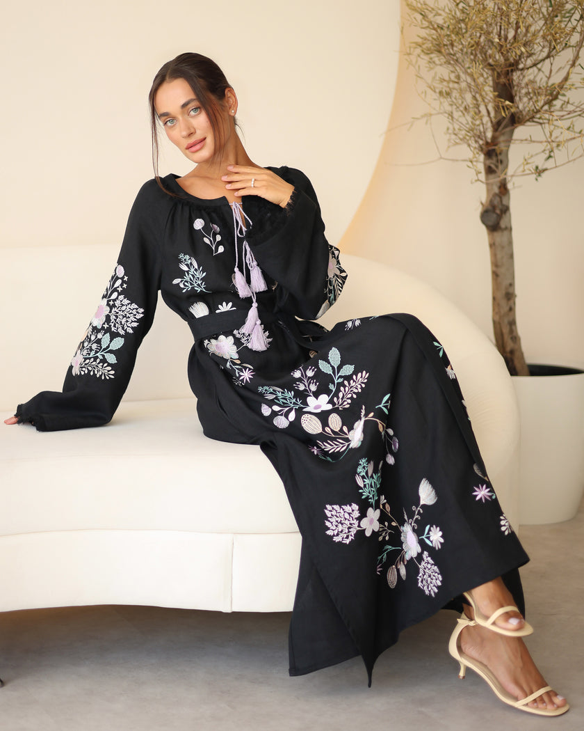 Black linen kaftan maxi dress with pastel floral embroidery and lilac tassel ties styled in lifestyle setting - Zalxndra Resort
