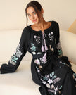 Seated view of black linen kaftan maxi dress with pastel floral embroidery and lilac tassel ties - Zalxndra Resort