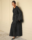 Black linen kaftan maxi dress with tonal floral embroidery, frayed bell sleeves, and tassel ties styled with feather clutch - Zalxndra Resort