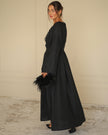 Side profile of black linen kaftan maxi dress with tonal floral embroidery and feather clutch - Zalxndra Resort