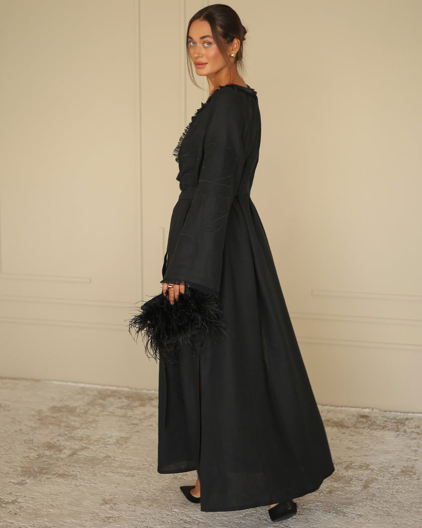 Side profile of black linen kaftan maxi dress with tonal floral embroidery and feather clutch - Zalxndra Resort