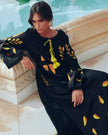 Black linen kaftan maxi dress with yellow and orange leaf embroidery, angel sleeves with frayed trim and yellow tassel ties, styled poolside, editorial view - Zalxndra Resort