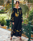 Black linen kaftan maxi dress with yellow and orange leaf embroidery, angel sleeves with frayed trim and tassel ties, lifestyle view - Zalxndra Resort