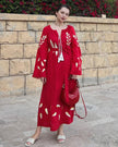 Scarlet red linen kaftan maxi dress with gold leaf embroidery, angel sleeves, frayed trim and tassel tie belt, styled with red handbag, lifestyle view - Zalxndra Resort