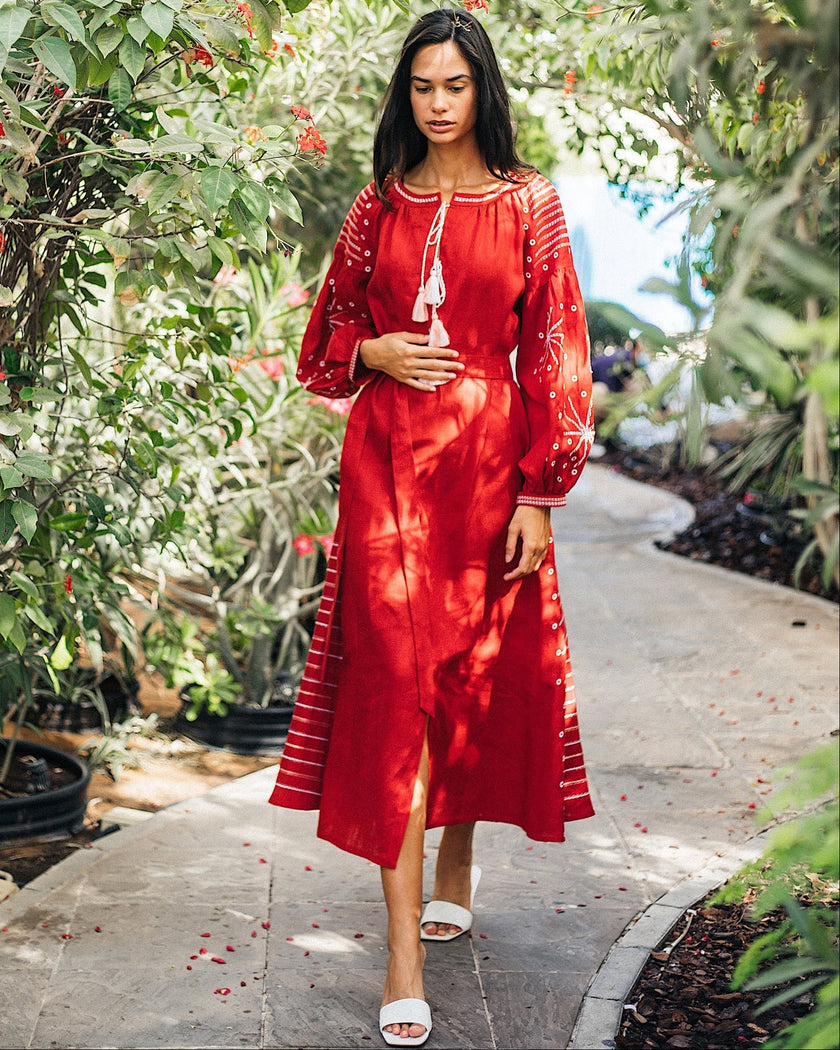 Cherry red linen kaftan maxi dress with white embroidery, balloon sleeves and tassel ties, garden lifestyle view - Zalxndra Resort