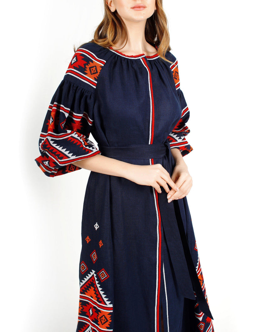 Navy blue linen kaftan maxi dress with red, orange, and white hand-embroidered cross-stitch on bodice and balloon sleeves, self-tie belt, bodice detail - Zalxndra Resort
