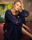 Seated model in navy linen kaftan maxi dress with orange and blue geometric embroidery and tassel ties - Zalxndra Resort