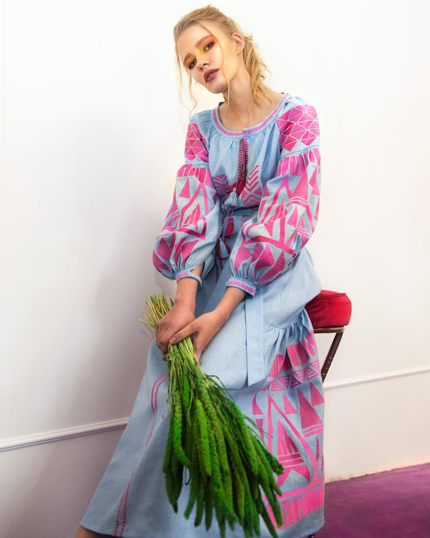 Powder blue linen kaftan maxi dress with pink geometric embroidery, balloon sleeves and tassel tie, editorial seated view - Zalxndra Resort
