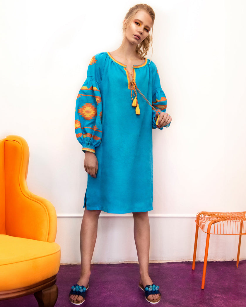 Full-length view of model in turquoise linen kaftan midi dress with orange geometric embroidery and tassel ties - Zalxndra Resort