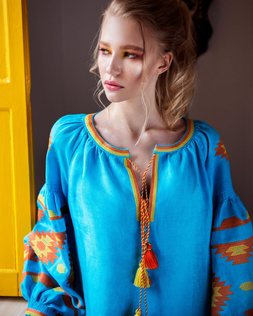 Portrait of model in turquoise linen kaftan midi dress with orange and yellow geometric embroidery and tassel ties - Zalxndra Resort