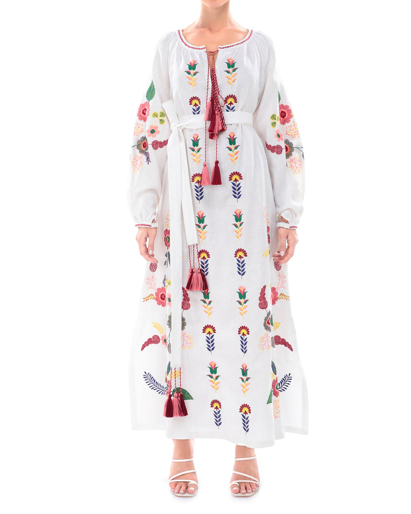 White linen kaftan maxi dress with multicolour folk floral embroidery, balloon sleeves, self-tie belt, and tassel ties on model, full-length view - Zalxndra Resort