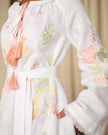 Close-up of pastel floral embroidery on sleeve and bodice of white linen kaftan with peach tassel ties — Zalxndra Resort