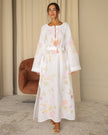 Full-length view of white pastel floral embroidered linen kaftan maxi dress styled with leather sandals — Zalxndra Resort