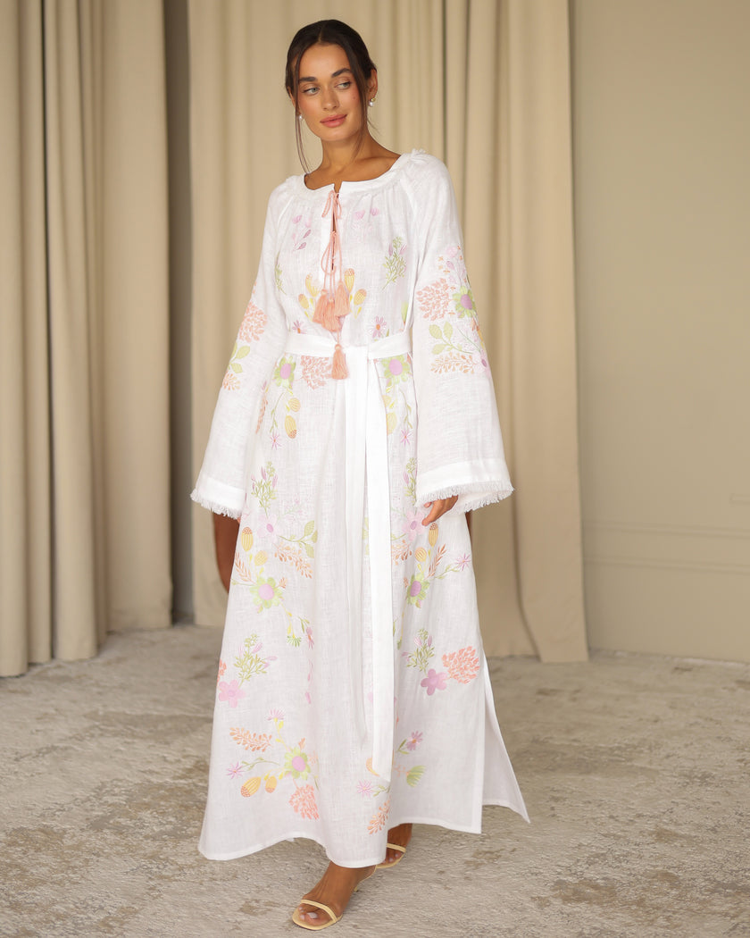 Model posing in white pastel floral embroidered linen kaftan maxi dress with peach tassel ties — Zalxndra Resort