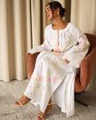 Model seated in white pastel floral embroidered linen kaftan maxi dress styled with leather sandals — Zalxndra Resort