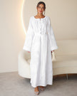 Full-length view of white linen kaftan maxi dress with tonal floral embroidery, frayed bell sleeves, and tassel ties - Zalxndra Resort