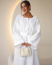 White linen kaftan maxi dress with tonal floral embroidery, frayed bell sleeves, and tassel ties styled with handbag - Zalxndra Resort