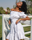 Editorial view of white linen off-shoulder mini dress with tonal lemon embroidery, puff sleeves, and ruffle hem - Zalxndra Resort