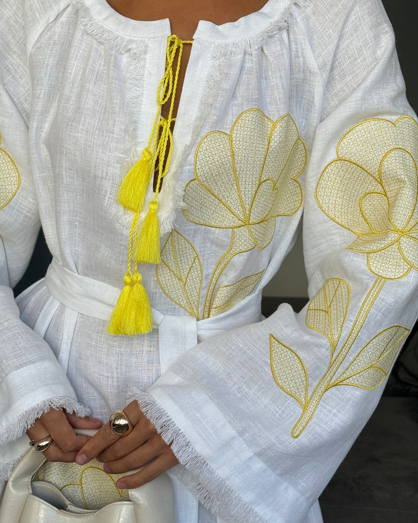 Close-up of yellow outlined floral embroidery, frayed sleeves, and tassel ties on white linen kaftan maxi dress - Zalxndra Resort